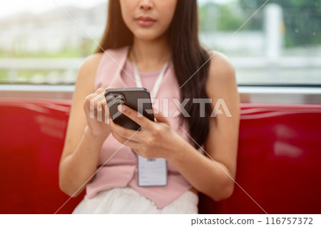 Cropped image of a thoughtful Asian female reading messages on her phone while taking the sky train. Cropped image of a thoughtful Asian female reading messages on her phone while taking the sky train. 116757372