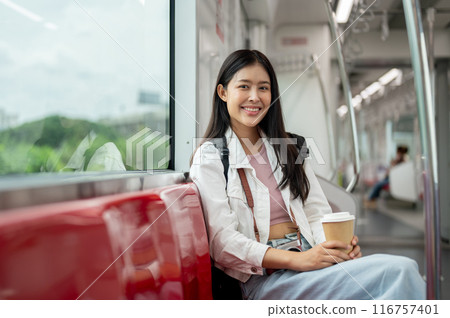 A smiling, beautiful young Asian female commuter is sitting on a seat in a sky train. A smiling, beautiful young Asian female commuter is sitting on a seat in a sky train. 116757401