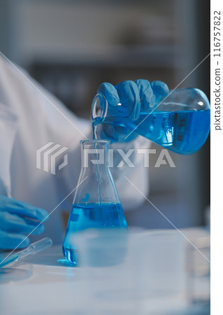 Group of dedicated scientist conduct chemical experiment in medical laboratory, carefully drop precise amount of liquid from pipette into test tube for vaccine drug or antibiotic development. Neoteric 116757822