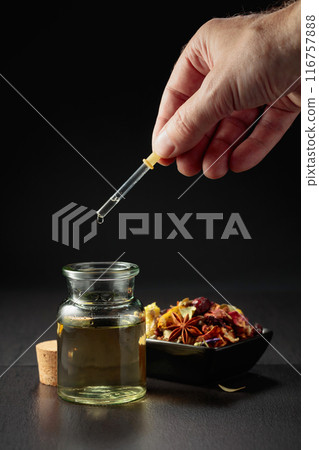 Dropping essential oil or herbal tincture into a small bottle. Dropping essential oil or herbal tincture into a small bottle. 116757888