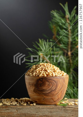 Peeled pine nuts and cedar branch on a old wooden table. 116757907
