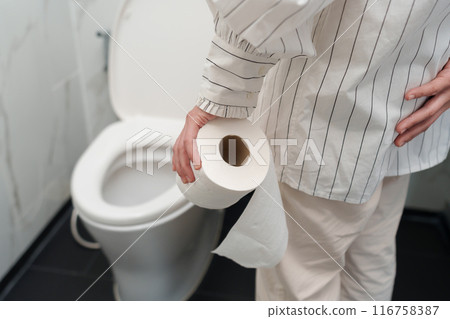 woman holding a roll of toilet paper with toilet bowl in bathroom 116758387