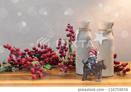 Christmas decoration on table. Branch with red berries and decorative vases. Statuette of little girl on horse. Christmas decoration on table. Branch with red berries and decorative vases. Statuette of little girl on horse. 116758638