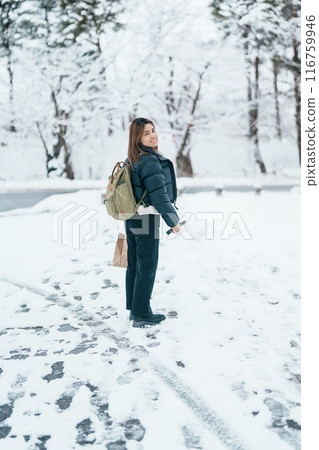 Traveler with Sweater and backpack walking on snow covered forest in frosty weather. Winter Travel, Adventure, Exploring and Vacation concept 116759946