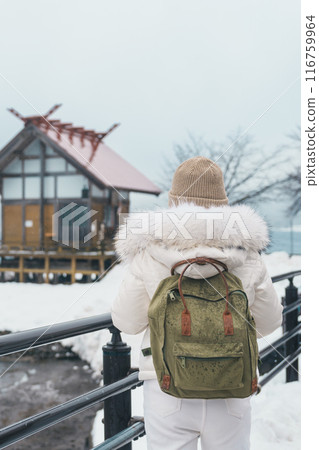 Woman tourist sightseeing Kansa Shrine and Lake Tazawa in winter. Traveler travel in Semboku city, Akita Prefecture, Japan. Landmark for tourist attraction in Tohoku region. Japan travel and vacation Woman tourist sightseeing Kansa Shrine and Lake Tazawa in winter. Traveler travel in Semboku city, Akita Prefecture, Japan. Landmark for tourist attraction in Tohoku region. Japan travel and vacation 116759964