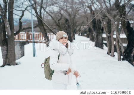 Woman tourist sightseeing sakura trees with snow. Happy traveler travel near Hinokinai River riverbank in winter season locate in Kakunodate town, Semboku District, Akita Prefecture, Japan 116759968