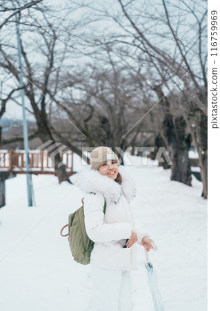 Woman tourist sightseeing sakura trees with snow. Happy traveler travel near Hinokinai River riverbank in winter season locate in Kakunodate town, Semboku District, Akita Prefecture, Japan 116759969