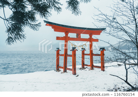 Red Japanese Torii gate of Goza no Ishi Shrine at lake tazawa in winter, located in Semboku city, Akita Prefecture, northern Japan. Landmark and famous for tourists attractions in Tohoku region, Japan 116760154