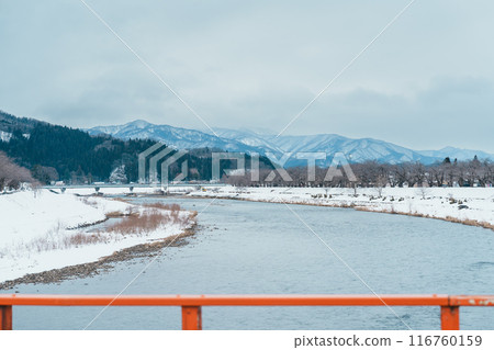 Hinokinai River riverbank with Yokomachi Bridge in winter season. Beautiful sakura trees flowers with snow and mountains locate in Kakunodate town, Semboku District, Akita Prefecture, Japan 116760159