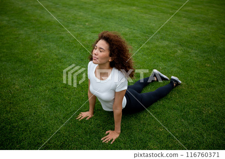 Beautiful curly girl warms up on the sports ground 116760371