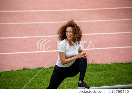 Beautiful curly girl warms up on the sports ground 116760430