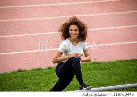Beautiful curly girl warms up on the sports ground 116760449
