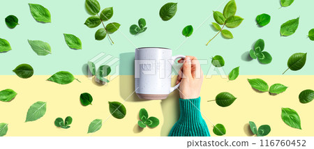 Person holding a mug with green leaves Person holding a mug with green leaves 116760452