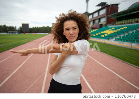Beautiful curly girl warms up on the sports ground Beautiful curly girl warms up on the sports ground 116760478