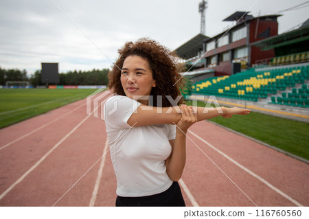 Beautiful curly girl warms up on the sports ground Beautiful curly girl warms up on the sports ground 116760560