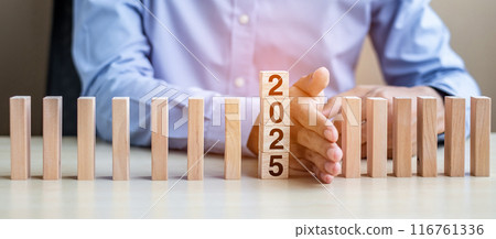Businessman hand Stopping Falling of 2025 wooden Blocks. Business, Risk Management, Insurance, Resolution, strategy, solution, goal, New Year New You and happy holiday concepts Businessman hand Stopping Falling of 2025 wooden Blocks. Business, Risk Management, Insurance, Resolution, strategy, solution, goal, New Year New You and happy holiday concepts 116761336