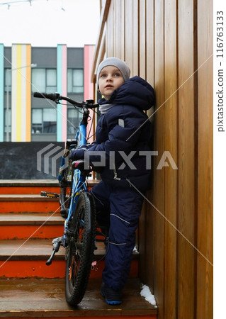 A Caucasian boy asked to take his bike for a walk in winter 116763133