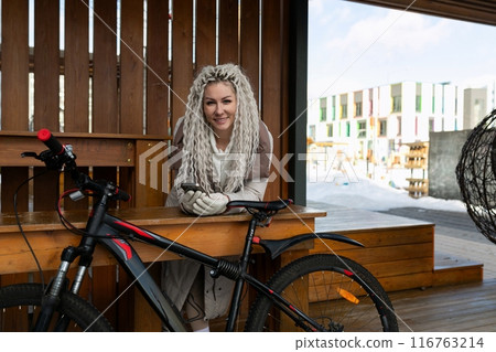 Woman Sitting at Table Next to Bike Woman Sitting at Table Next to Bike 116763214
