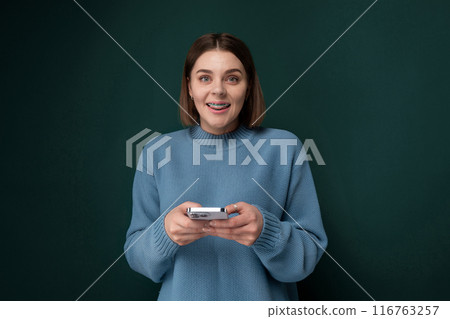 Woman in Blue Sweater Holding Cell Phone Woman in Blue Sweater Holding Cell Phone 116763257
