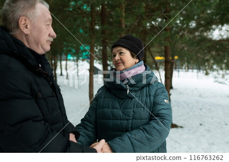Cute mature couple experiencing love for each other while walking in the park in winter 116763262