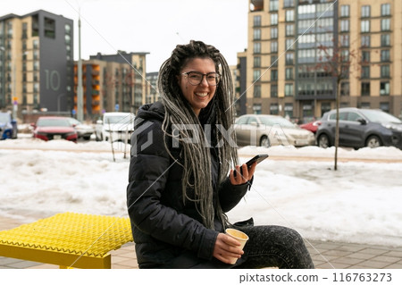 Urban pretty woman with dreadlock braid hairstyle walks along the street with snow 116763273