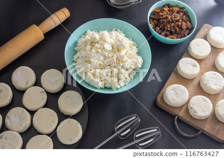 Cheesecakes made from cottage cheese and raisins. Prepare food for breakfast. Syrnik pancakes. Round cheese cake on black background. 116763427