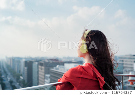 一位女士在博多站的屋頂上一邊聽音樂一邊向外張望 116764387