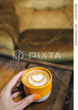 A warm cup of coffee with a heart-shaped design on wooden table A warm cup of coffee with a heart-shaped design on wooden table 116764388