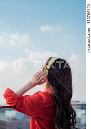 一位女士在博多站的屋頂上一邊聽音樂一邊向外張望 一位女士在博多站的屋頂上一邊聽音樂一邊向外張望 116764390