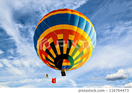 Colorful hot air balloon flying over blue sky with white clouds 116764473