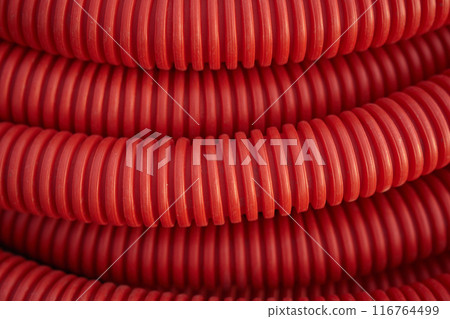 Corrugated for insulation cable of wires underground, plastic tube, electricity protection pipe for construction works, red corrugation close-up with copy space. High quality photo 116764499