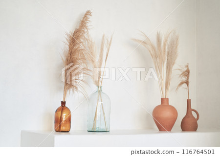 Podium in boho style. Product display with c plants and flowers in amber glass, natural mock up with copy space. White wall and beige colours. High quality photo 116764501