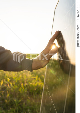 Close-up of a hand touching a solar panel at sunset Close-up of a hand touching a solar panel at sunset 116764990
