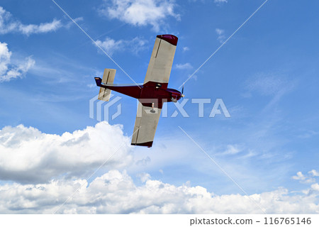 Single engine ultralight plane flying in the blue sky with white clouds Single engine ultralight plane flying in the blue sky with white clouds 116765146