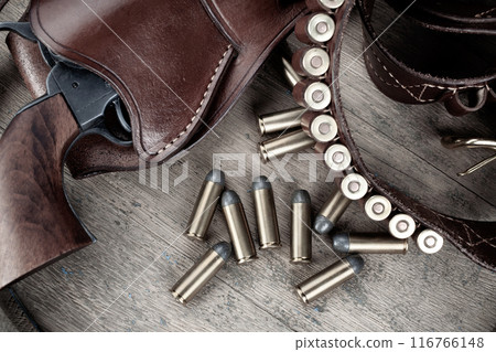 Colt Revolver and gun belt with ammunition on wooden barrel. Top view. 116766148