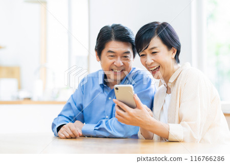 A middle-aged couple relaxing at the dining room 116766286