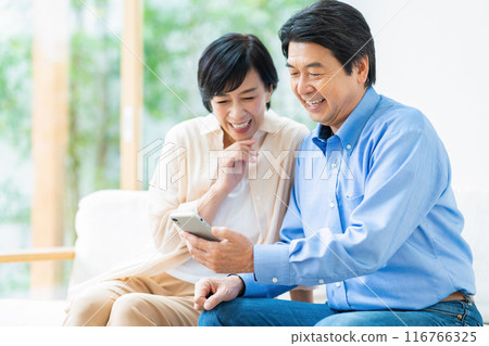 A middle-aged couple relaxing in the living room 116766325