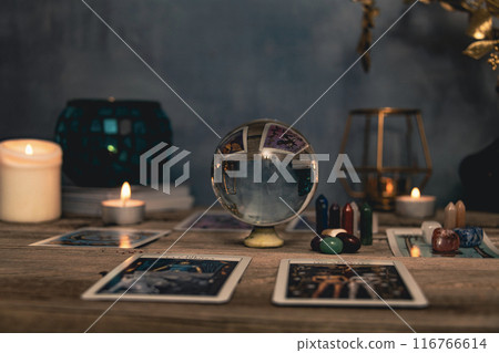 Tarot cards including The Fool and The Lovers alongside crystals and candles on a textured wooden table. 116766614