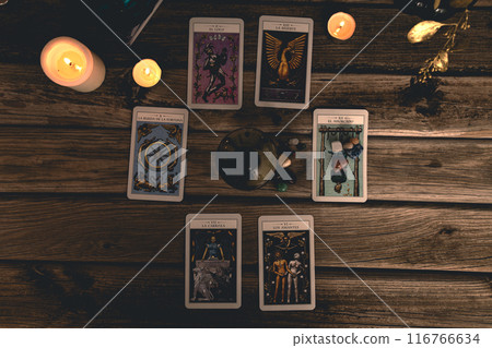 Tarot cards including The Fool and The Lovers alongside crystals and candles on a textured wooden table. Tarot cards including The Fool and The Lovers alongside crystals and candles on a textured wooden table. 116766634