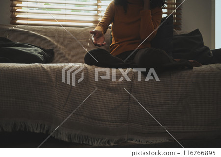 Upset woman sitting on sofa, suggesting a thoughtful or conversational moment in dark room Upset woman sitting on sofa, suggesting a thoughtful or conversational moment in dark room 116766895