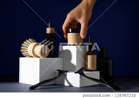 Shaving tools, bottles of men's cosmetics and hand on dark blue background 116767218