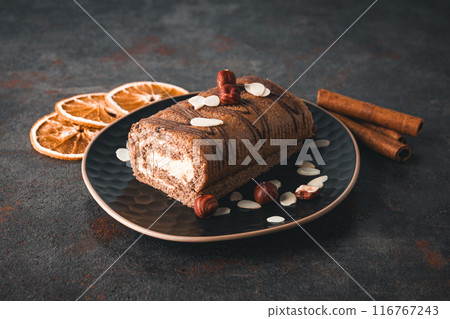 Roll cake in a bowl with dried oranges on a dark background Roll cake in a bowl with dried oranges on a dark background 116767243
