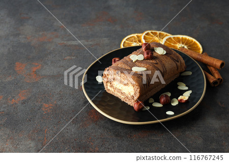 Roll cake in a bowl with dried oranges on a dark background Roll cake in a bowl with dried oranges on a dark background 116767245