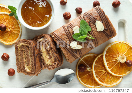 Roll cake with dried oranges and nuts on a light background Roll cake with dried oranges and nuts on a light background 116767247