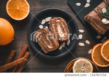 Roll cake in a bowl with fresh oranges on a dark background 116767250