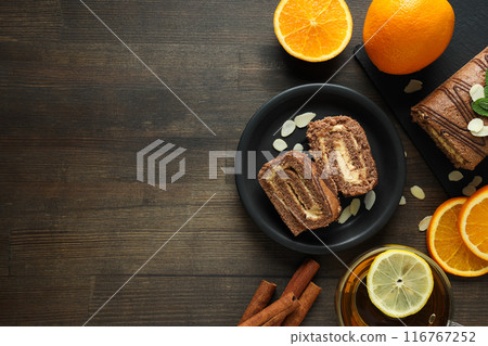 Roll cake in a bowl with fresh oranges on a dark background Roll cake in a bowl with fresh oranges on a dark background 116767252