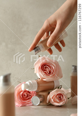 Bottles of foundation, female hand and roses on light background Bottles of foundation, female hand and roses on light background 116767299