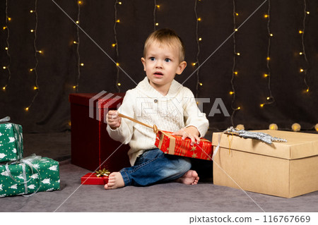 Little two-year-old boy opens Christmas gifts at home 116767669
