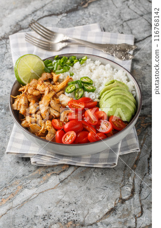 Mexican rice bowl with chicken carnitas, cherry tomatoes, avocado, peppers close-up. Vertical Mexican rice bowl with chicken carnitas, cherry tomatoes, avocado, peppers close-up. Vertical 116768142