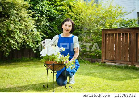 一位微笑的中年婦女正在種樹 116768732